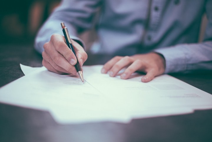 Hands signing a document